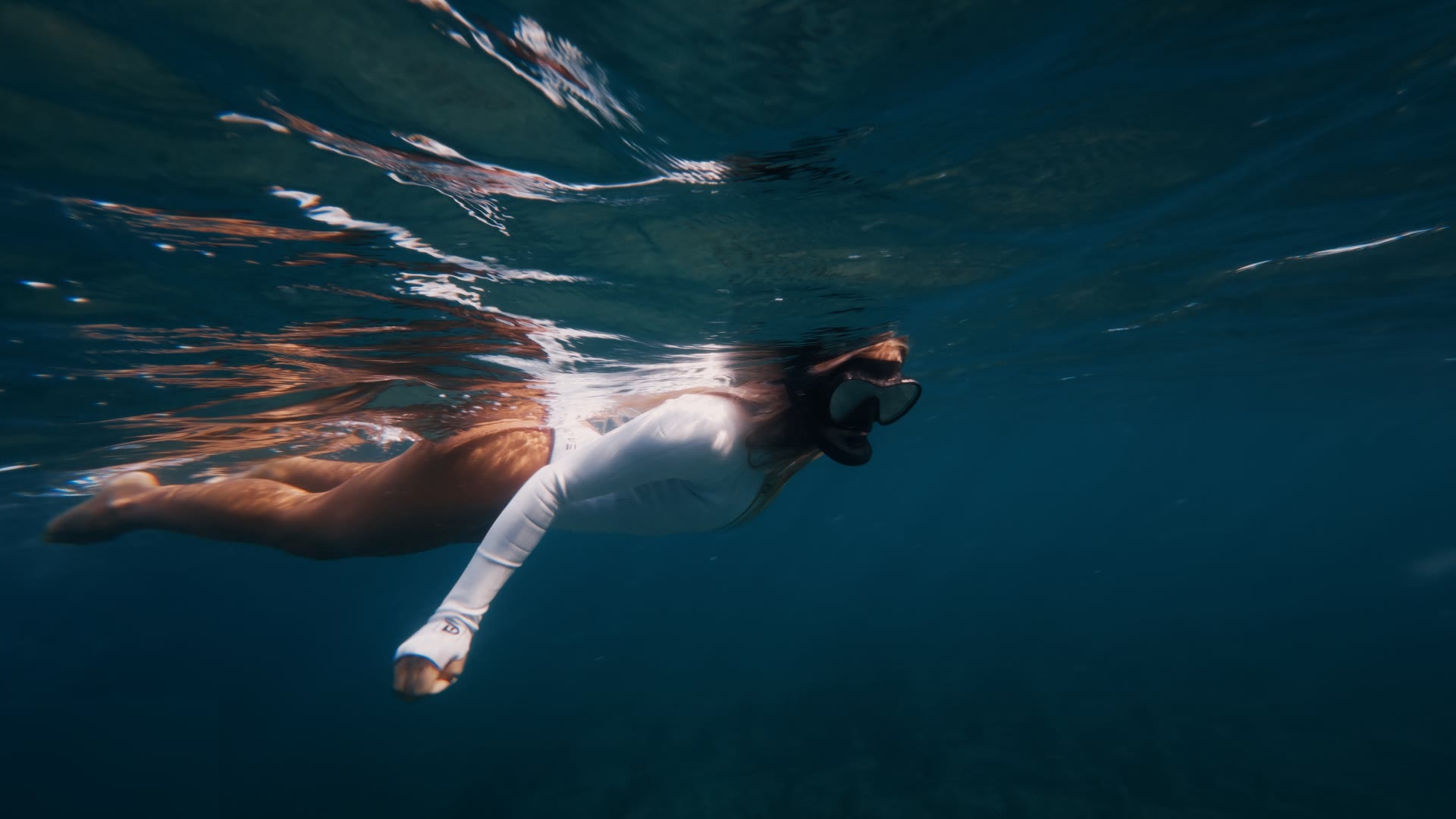 Swimmer in a white suit near the surface, graded with AQUA PG